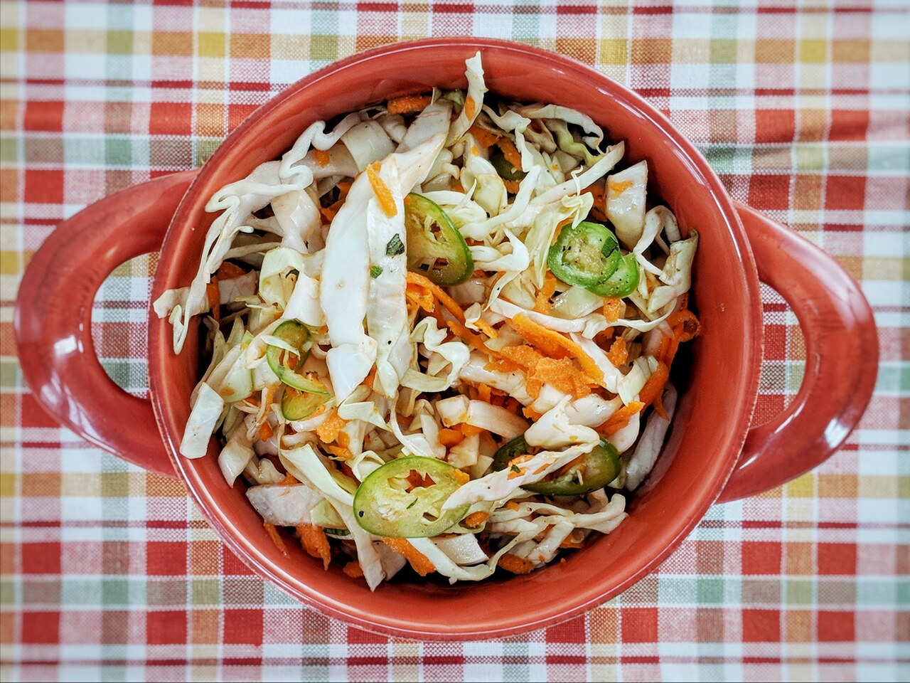 Whole ingredients for curtido on a kitchen counter: green cabbage, carrots, white onion, garlic, dried oregano, vinegar, and kosher salt