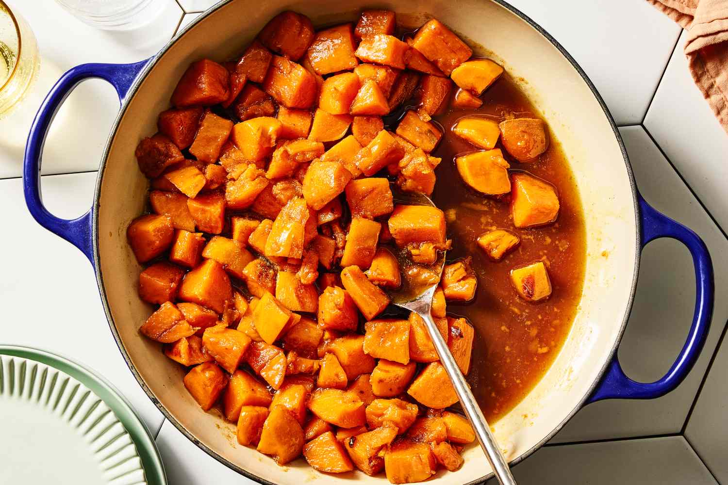 Whole peeled yams, brown sugar, butter, cinnamon, nutmeg, vanilla, salt, and orange juice arranged on a warm-lit kitchen counter
