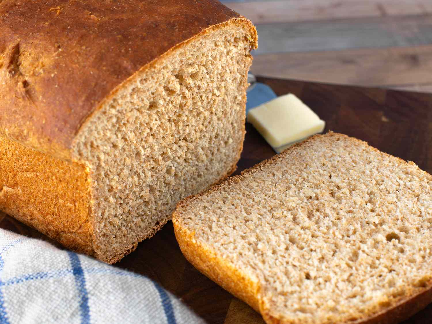 Whole wheat flour, bread flour, honey, yeast, and salt arranged in small bowls on a kitchen counter with a mixing bowl nearby