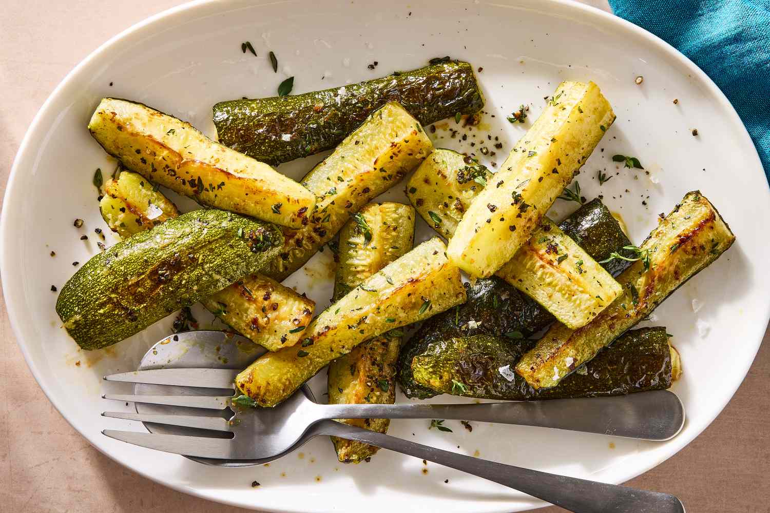 Whole zucchini, grated Parmesan, garlic, olive oil, salt, pepper, and Italian seasoning arranged on a tidy kitchen counter with warm natural light