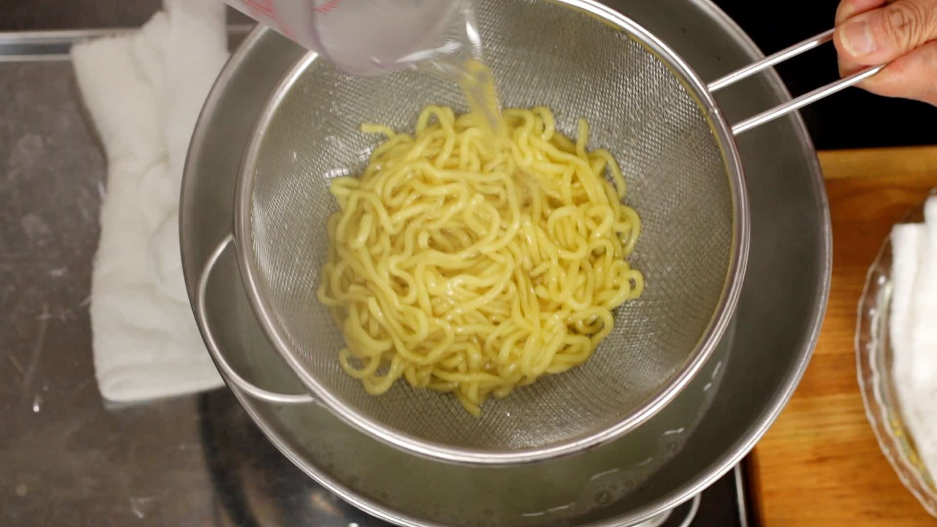 Yakisoba noodles draining in a colander over a sink
